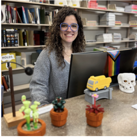 Photo of the librarian Jackie Huddle. She has curly brown hair and wear glasses.