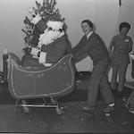 Man pushing Santa Claus in sleigh at Christmas party