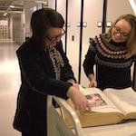 Two women looking at open book